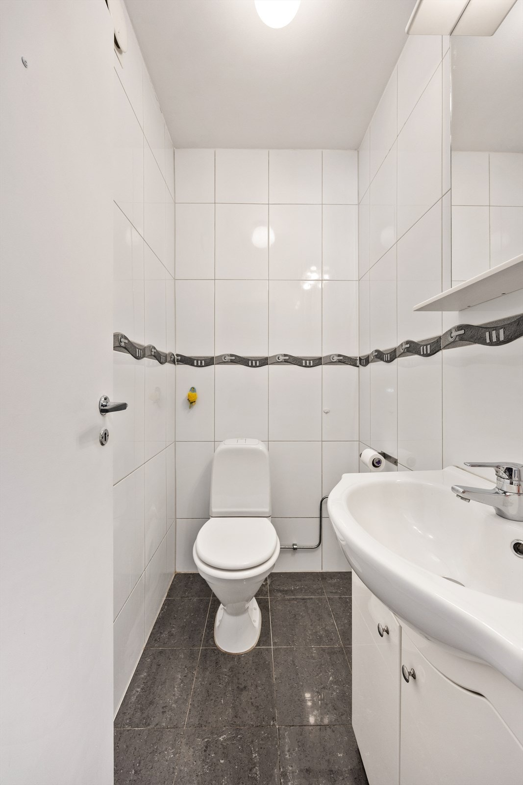 Separat toalettrom med flislagte overflater, utstyrt med toalett og servant. Galleribilde