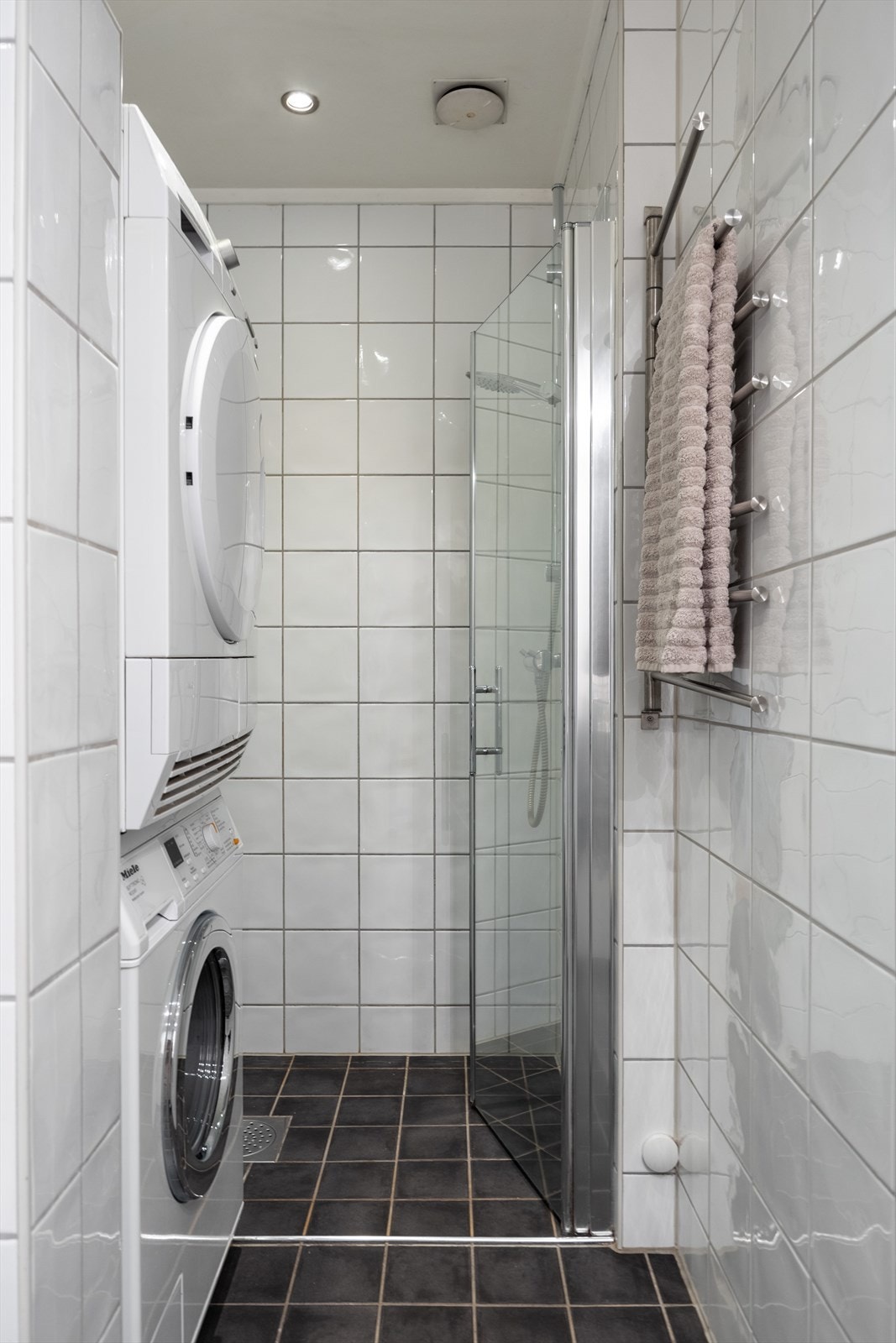 Baderommet er utstyrt med dusjnisje, opplegg for vaskemaskin, servantskap, veggmontert wc og stoppekran. Galleribilde