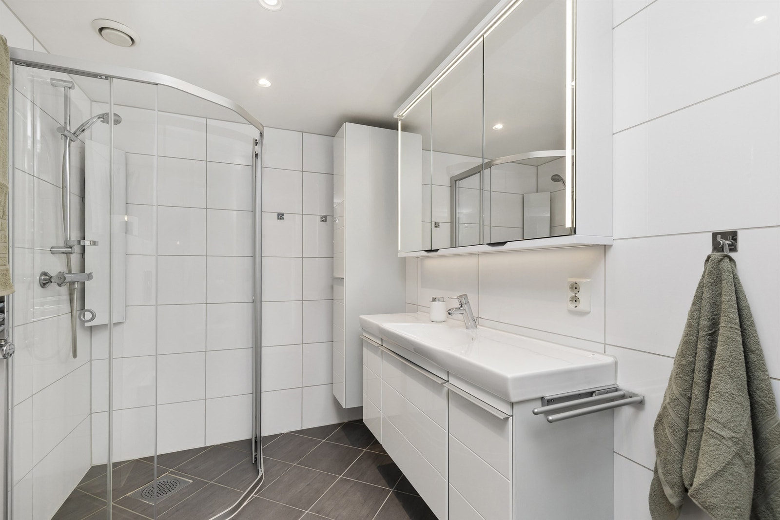 Badet er utstyrt med vegghengt toalett og et dusjhjørne med innfellbare glassdører. Galleribilde
