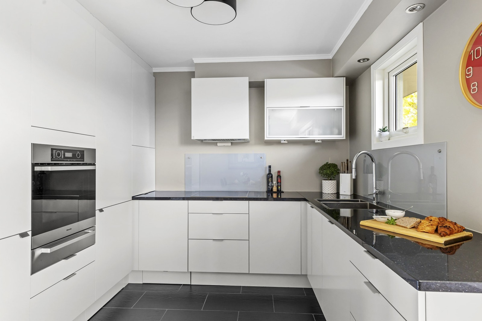 Kjøkkeninnredning fra HTH med benkeplate i stein og integrerte hvitevarer som medfølger. Hvitevarer er levert av Miele og oppvaskmaskin fra Siemens. Galleribilde