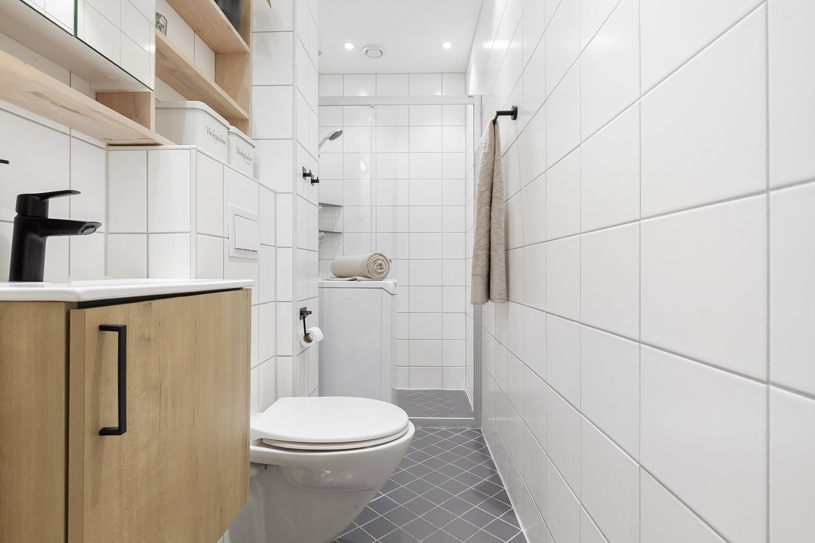Badet har dusjhjørne, opplegg for vaskemaskin og praktiske oppbevaringshyller Galleribilde