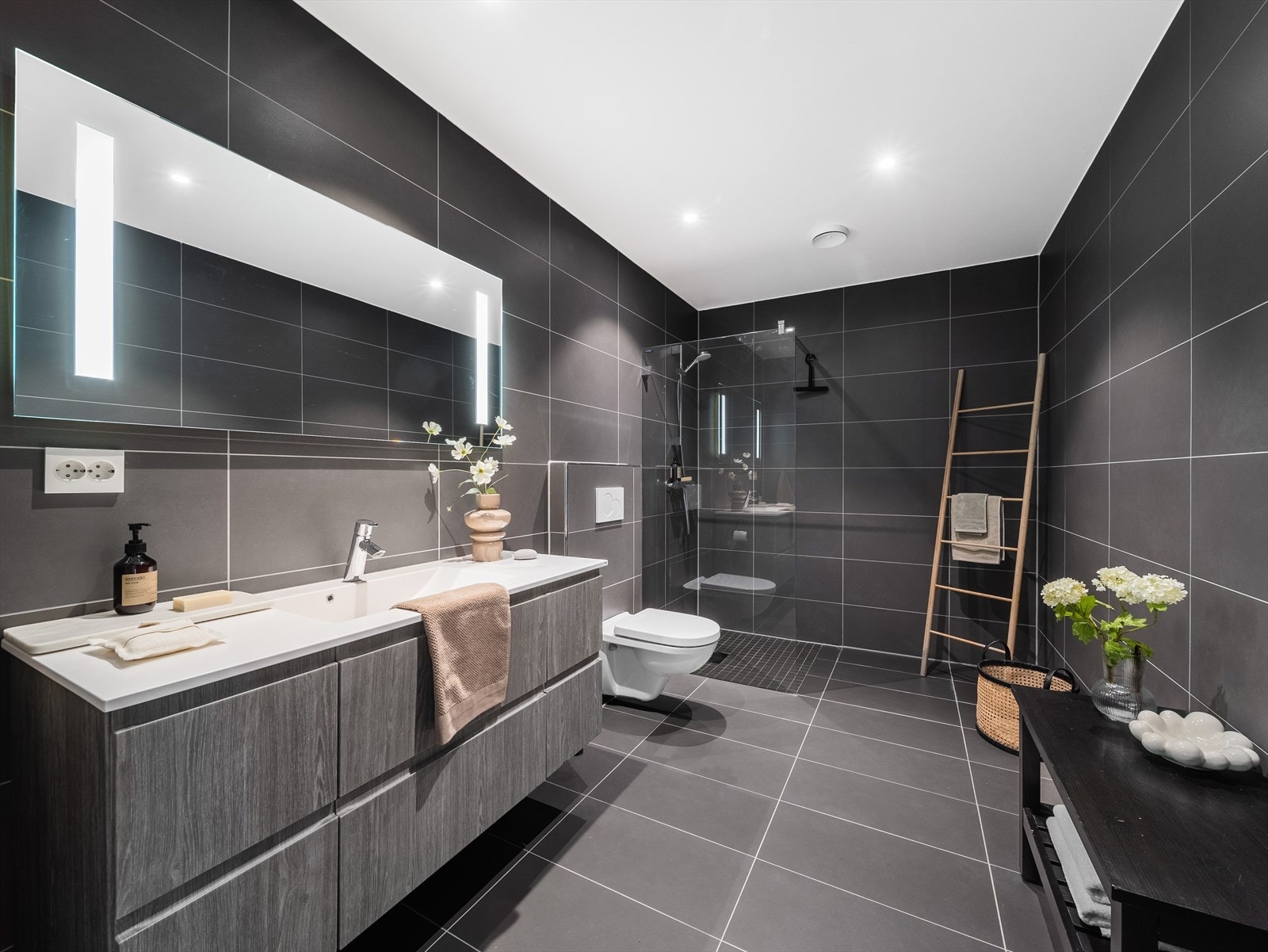 Badet i leilighetens hovedetasje er stort og stilrent utført med fliser på gulv og vegger, elektriske varmekabler i gulvet og LED-downlights i malt himling. Galleribilde