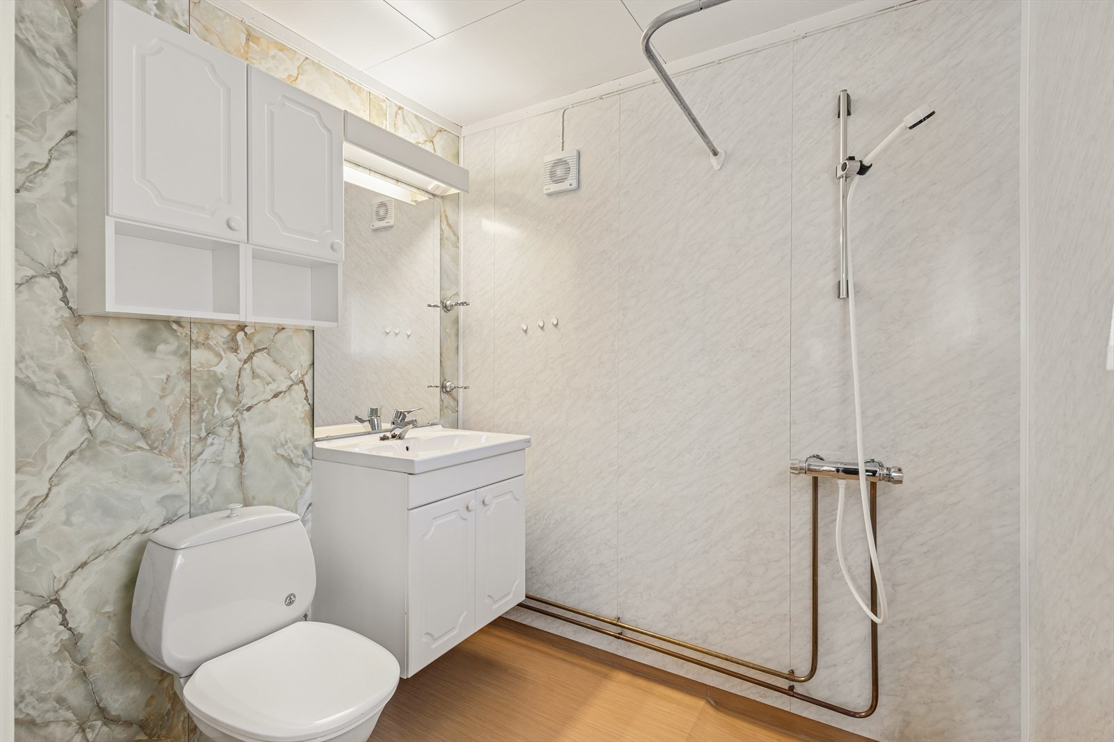 Badet er utstyrt med dusj med forheng, servant med underskap og gulvmontert toalett. Galleribilde