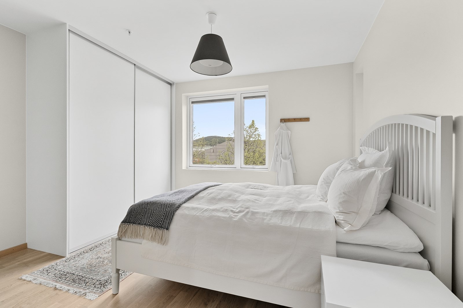 Lyst og romslig soverom med plassbygget skyvedørsgarderobe. Galleribilde