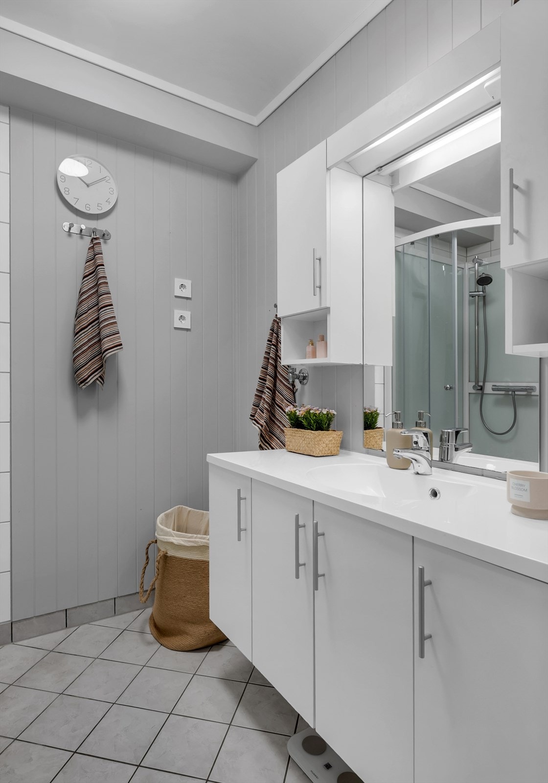 Badet har fliser på gulvet og vegger av panel, med moderne sanitærinnredning. Galleribilde