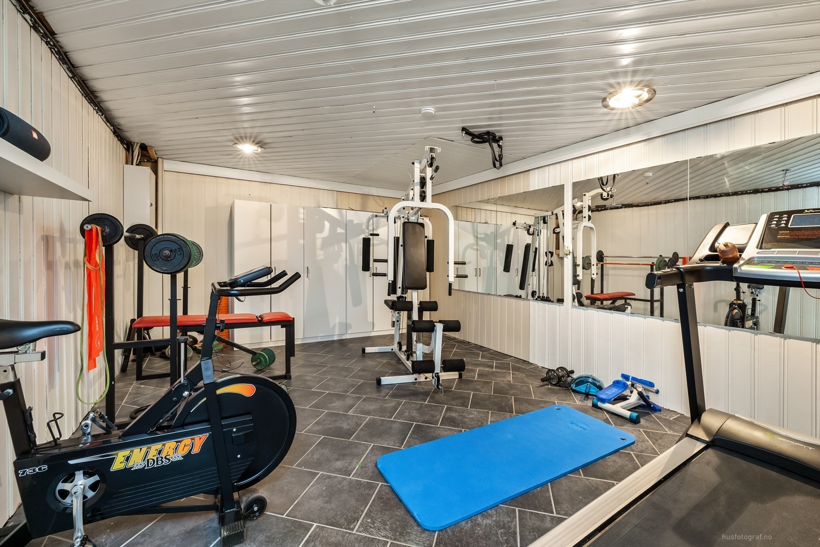 Eget trimrom i underetasjen med panel på veggene gir gode muligheter for trening hjemme. Galleribilde
