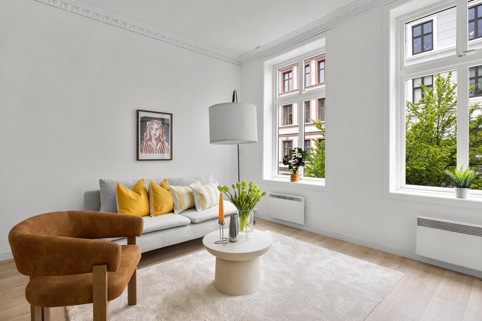 Lys og innbydende stue møblert med sofa, stol, stuebord og belysning. Galleribilde