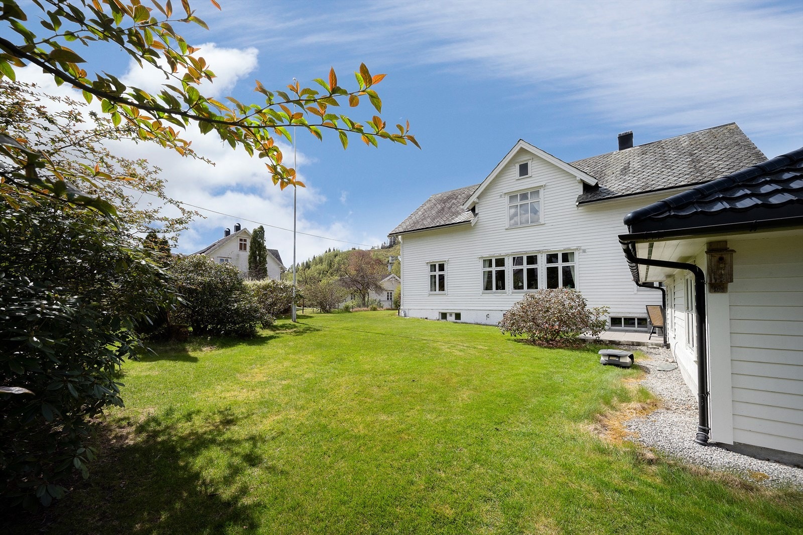 Tomten er pent opparbeidet med hage med grøntareal, planter og blomsterbedd. Galleribilde