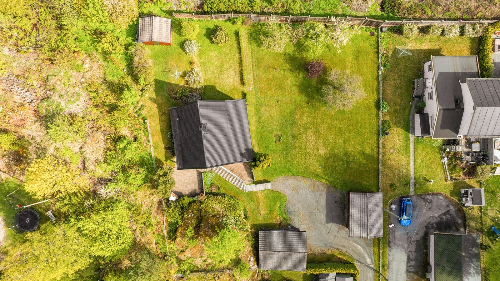 Eneboligen er plassert på en romslig tomt med hage, garasjer og uthus. Galleribilde