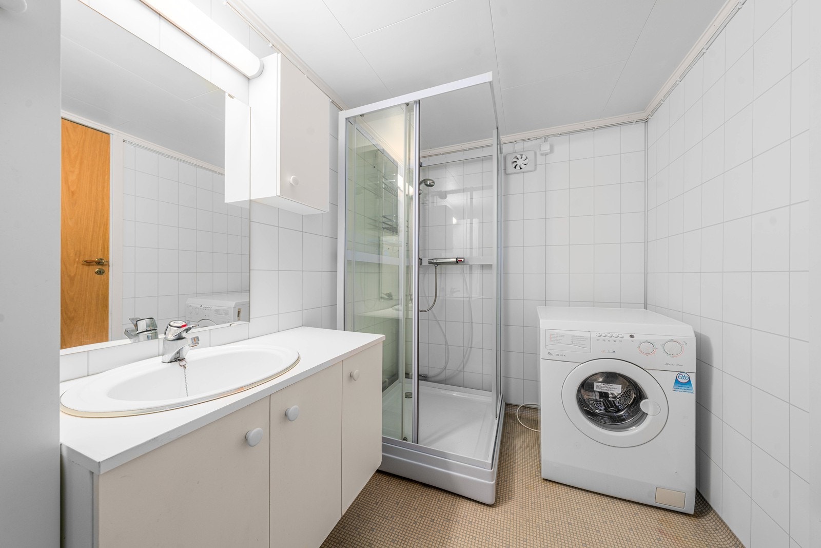 Badet i kjelleren har belegg på gulv, våtromsplater på veggene, dusjnisje og opplegg for vaskemaskin. Galleribilde