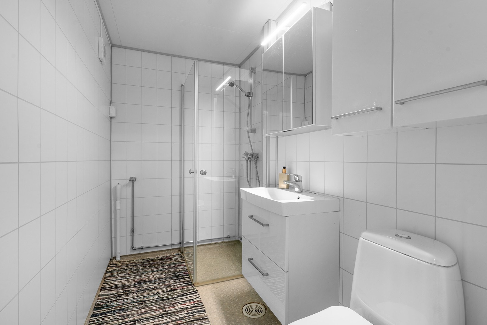 Badet er utstyrt med dusjnisje med glassdører og har opplegg for vaskemaskin. Galleribilde