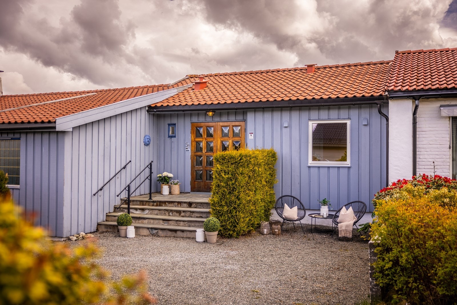 Gruslagt gårdsplass med plass til sittegruppe ved inngangspartiet. Flott dobbeldør inn i boligen. Galleribilde