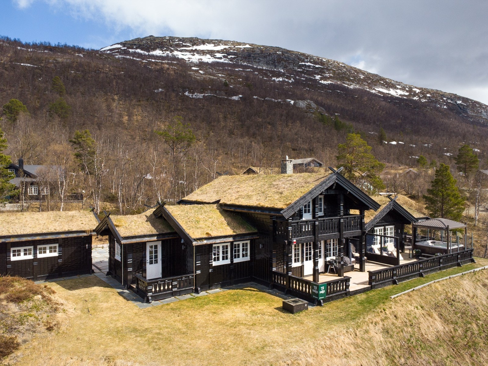 Hytta ligger høyt og fritt i terrenget med utsikt over hyttefeltet og fjellene. Galleribilde