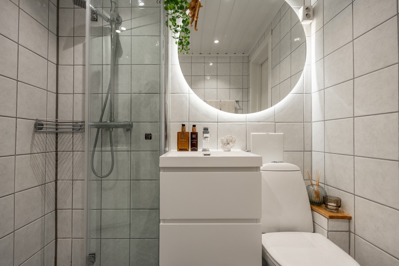 Badet er innredet med servantinnredning med servant, speil med belysning, dusjhjørne med dører i glass, toalett, samt plass og opplegg for vaskemaskin. Galleribilde