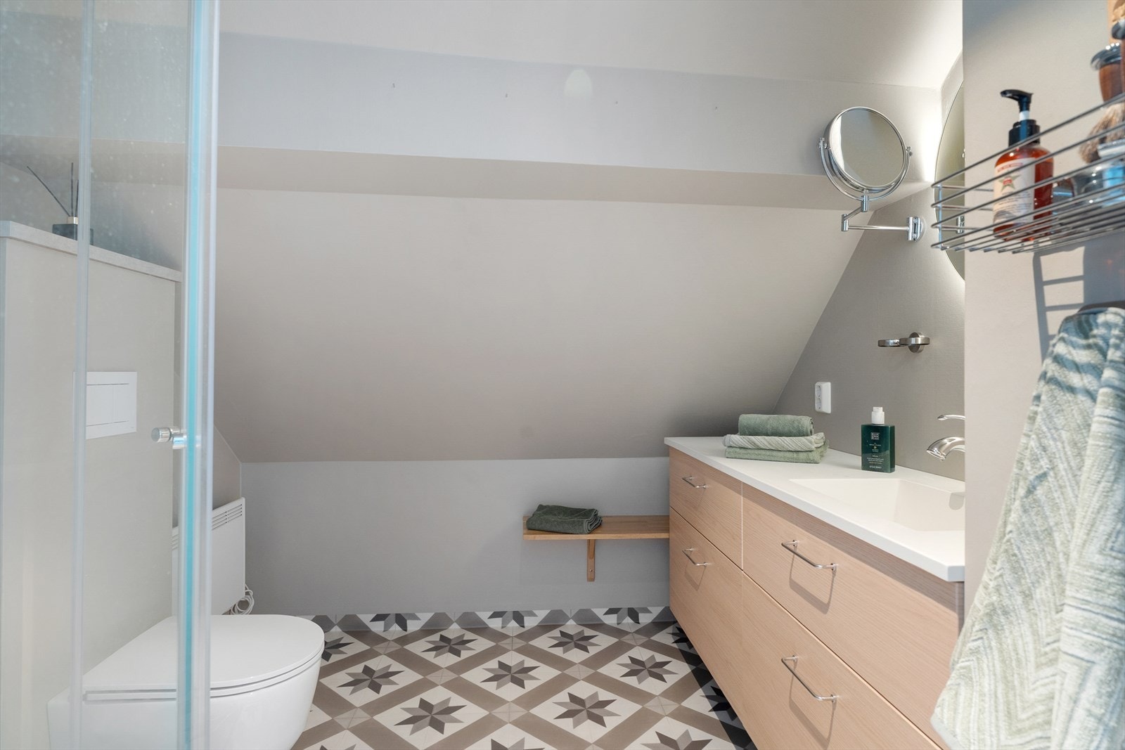 Badet i loftsetasjen ble pusset opp i 2021. Rommet har dusjkabinett, seksjon med heldekkende vask og veggmontert toalett. Vegger og tak har malte plater med våtromssystem, og gulvet har vinylbelegg. Galleribilde