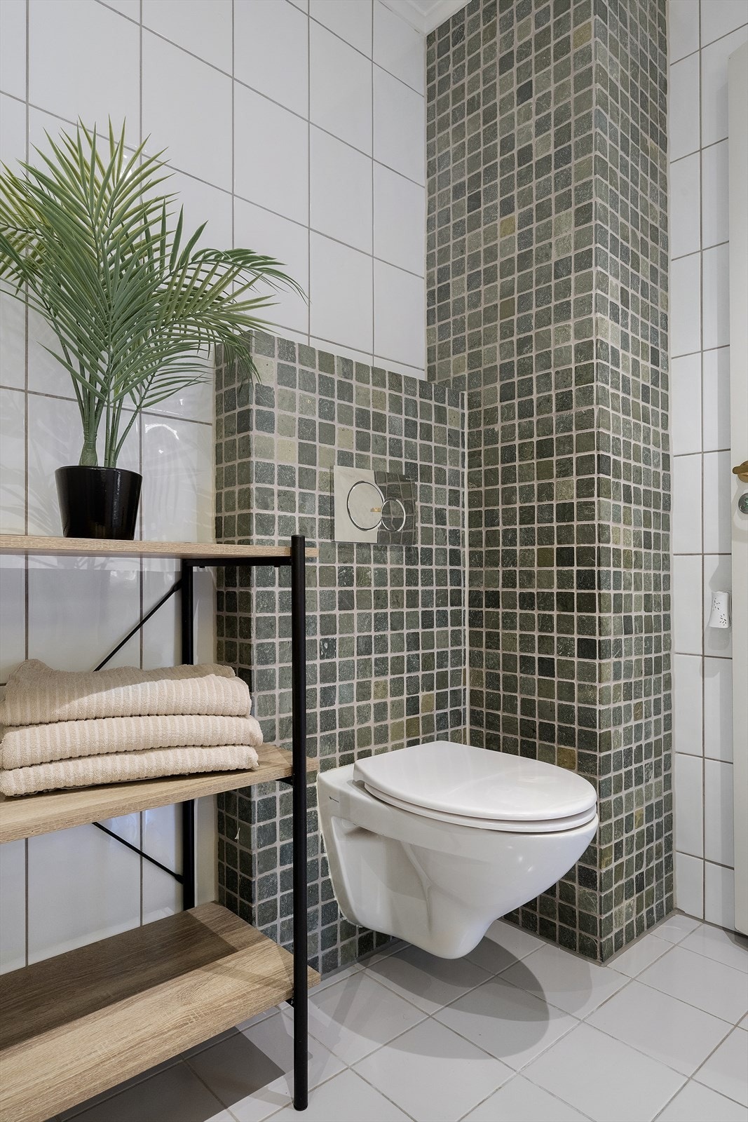 Detalj frå badet med vegghengt toalett og mosaikkfliser. Galleribilde