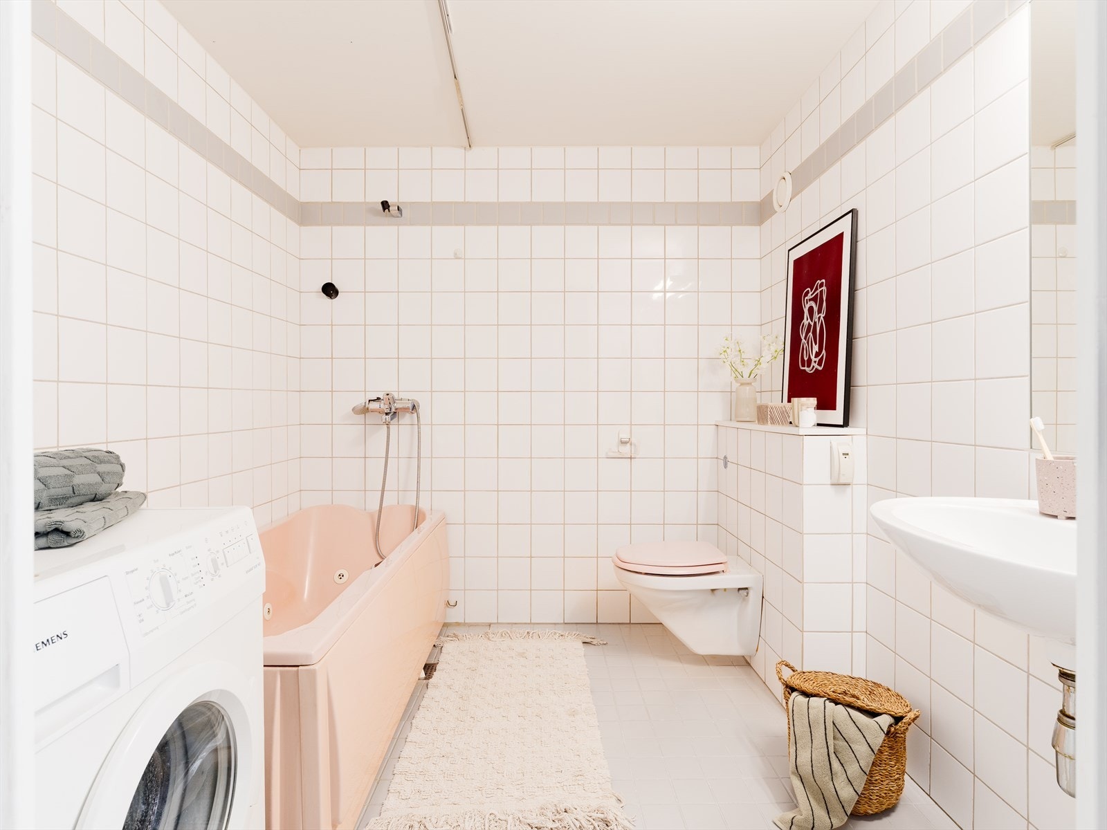 Baderom med fliser på gulv og vegger. Badet er utstyrt med gulvvarme, servant, veggfestet toalett og badekar samt opplegg for vaskemaskin. Galleribilde