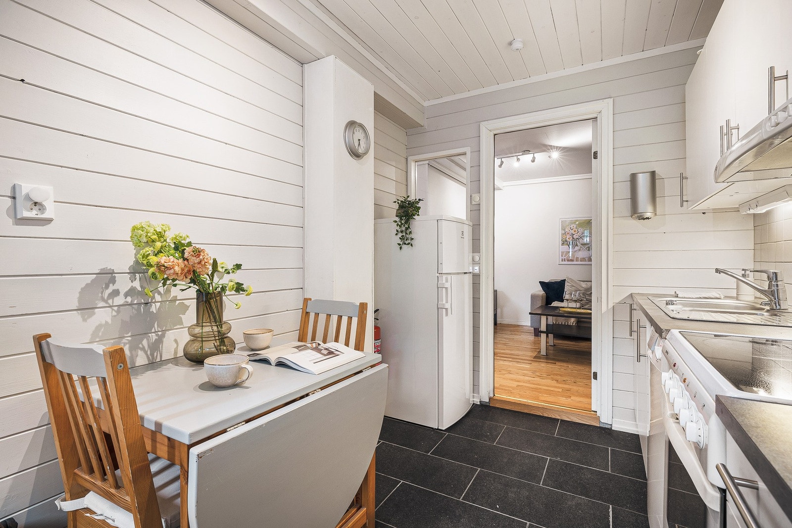 Funksjonelt kjøkken med slette fronter, laminert benkeplate og stålvask. Kjøkkenet er utstyrt med løse hvitevarer som komfyr, oppvaskmaskin og kjøle-/fryseskap, og fremstår praktisk med god utnyttelse av plassen. Galleribilde