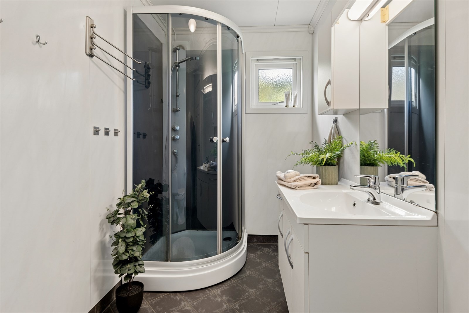 Badet ligger i boligens 1. etasje og er innredet med toalett, dusjkabinett og servant med innredning. Galleribilde