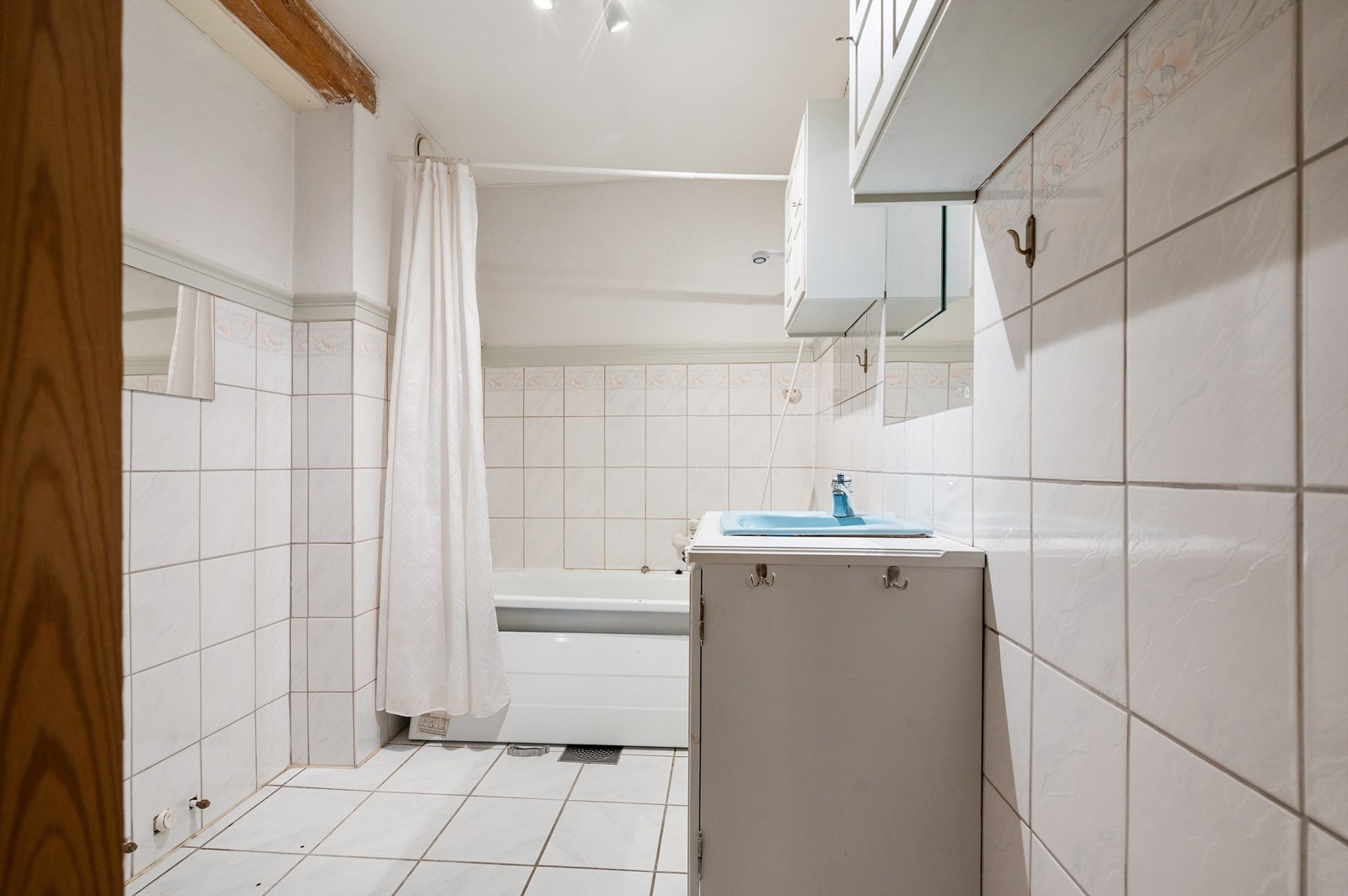 Baderom 2 har en kombinasjon av flislagte og malte vegger, utstyrt med frittstående badekar, vegghengt toalett og servantskap med profilerte fronter og ovenpåliggende vask. Galleribilde