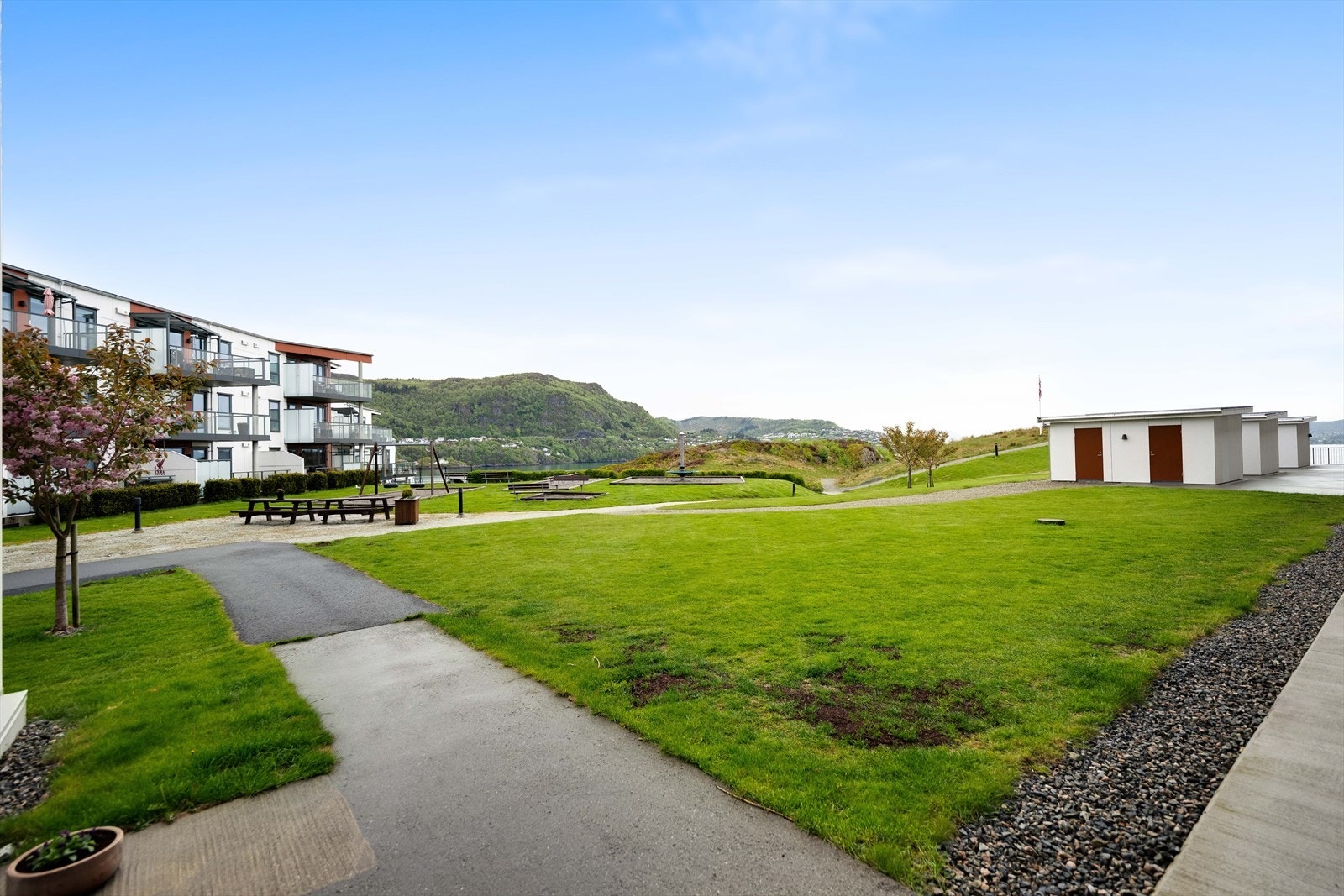 Rett utenfor døren på baksiden av leiligheten er det også opparbeidet fellesareal med lekeplasser, gangsti langs sjøen og felles bodareal. Det er èn tilhørende utvendig bod til leiligheten. Galleribilde