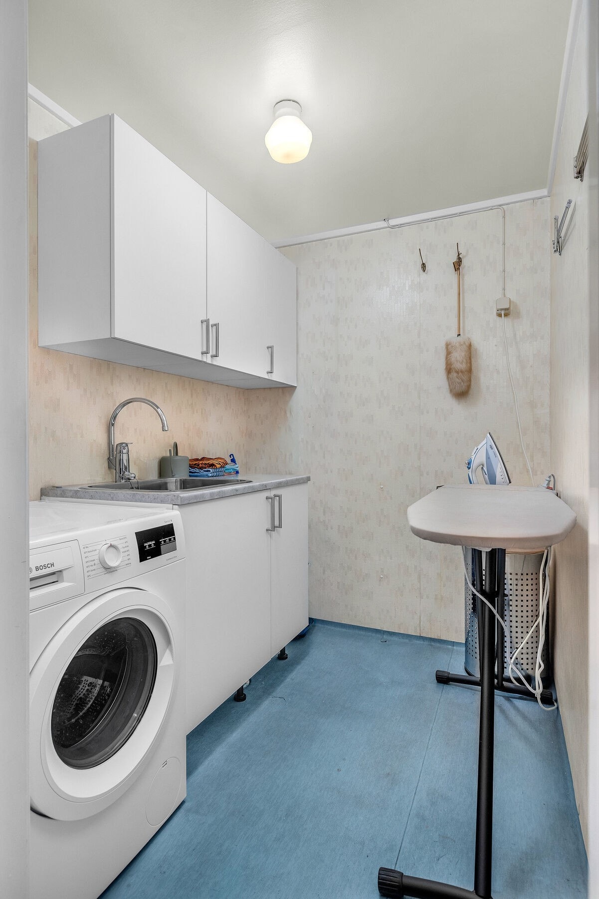Eget vaskerom med opplegg for vaskemaskin, skyllekar og praktisk benkeplass. Rommet har varmekabler i gulvet. Galleribilde