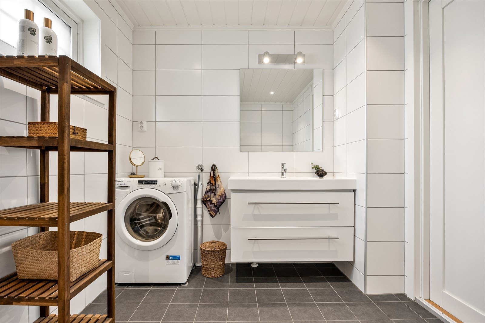 Badet er innredet med servant i baderomsinnreding, speil, toalett, opplegg for vaskemaskin og dusjhjørne. Galleribilde