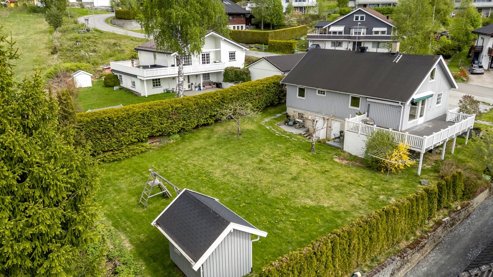 Romslig hage med plen og beplantning. Hagen er skjermet med hekk på begge sider mot naboene. Galleribilde