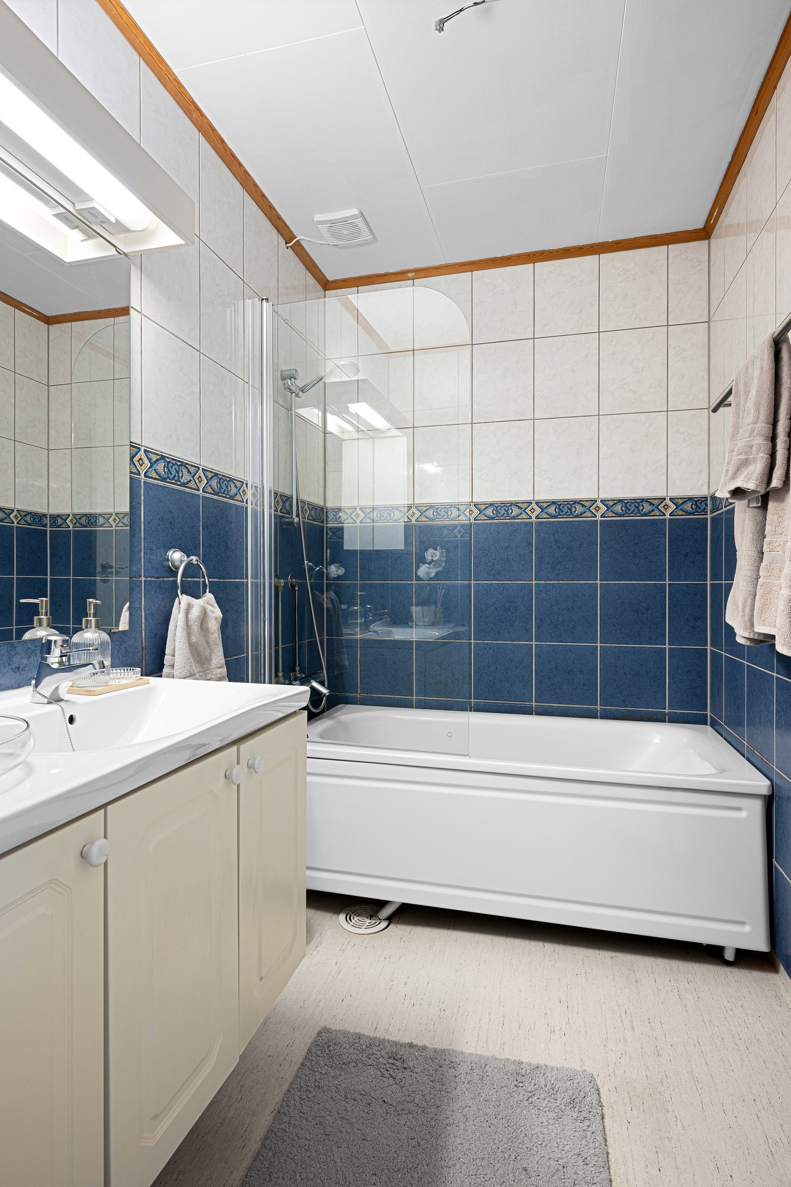 Badekar med dusjvegg og servant i innredning med speil og overskap Galleribilde