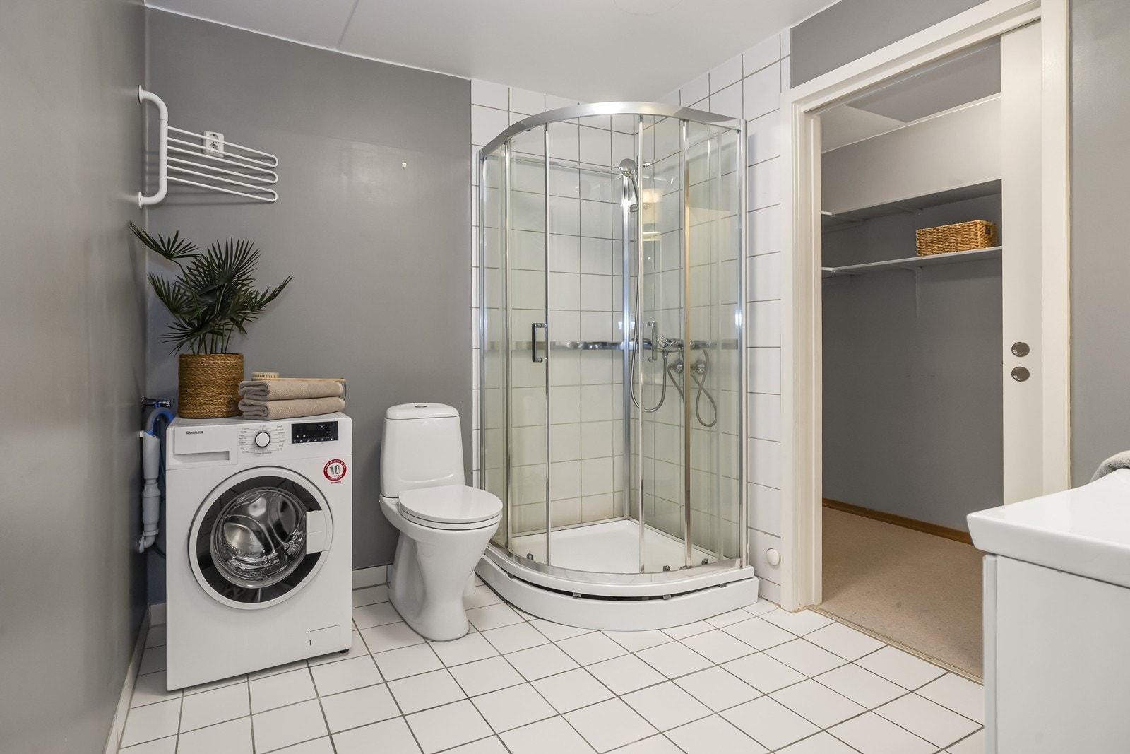 Badet har flislagt gulv med elektriske varmekabler, dusjkabinett og opplegg for vaskemaskin. Galleribilde