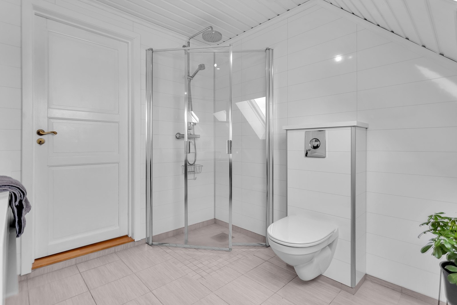 En praktisk dusjnisje med plassbesparende glassvegger og dusjhode med fossefallsfunksjon. Badet er videre utstyrt med servant med underskuffer samt vegghengt toalett. Galleribilde