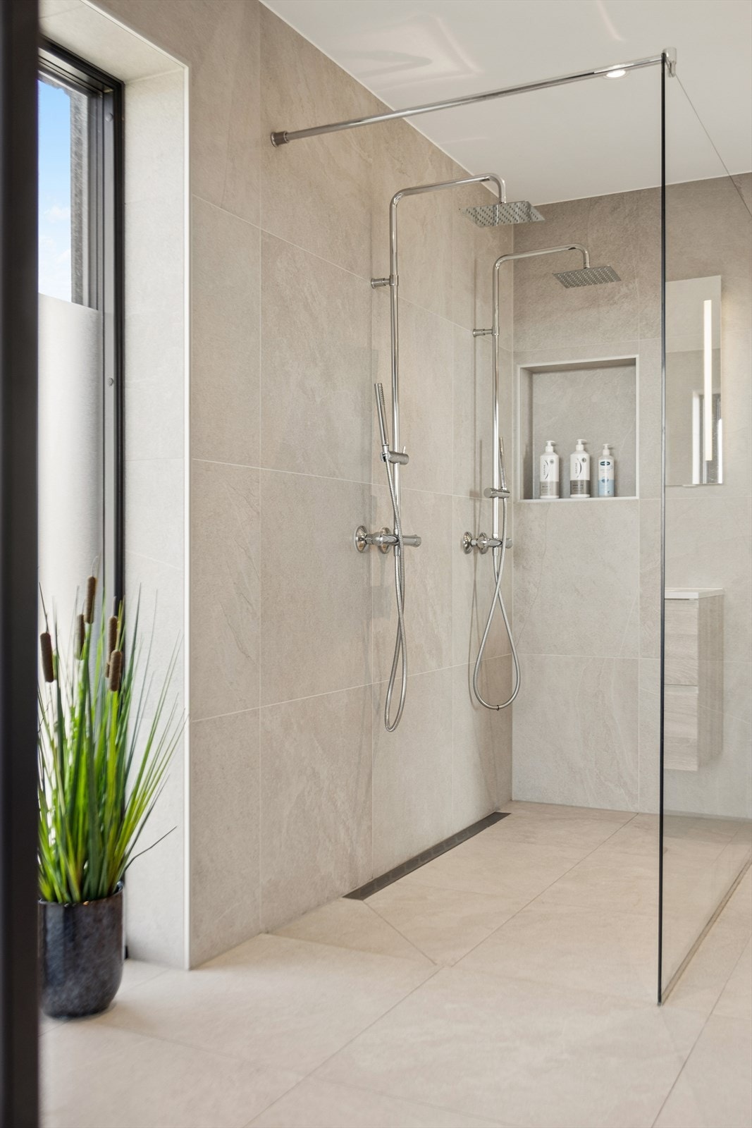 Videre inneholder badet både badekar og en romslig dusjnisje med to dusjgarnityrer. Dette gjør badet godt tilrettelagt både for hektiske morgener og rolige stunder med egenpleie. Galleribilde