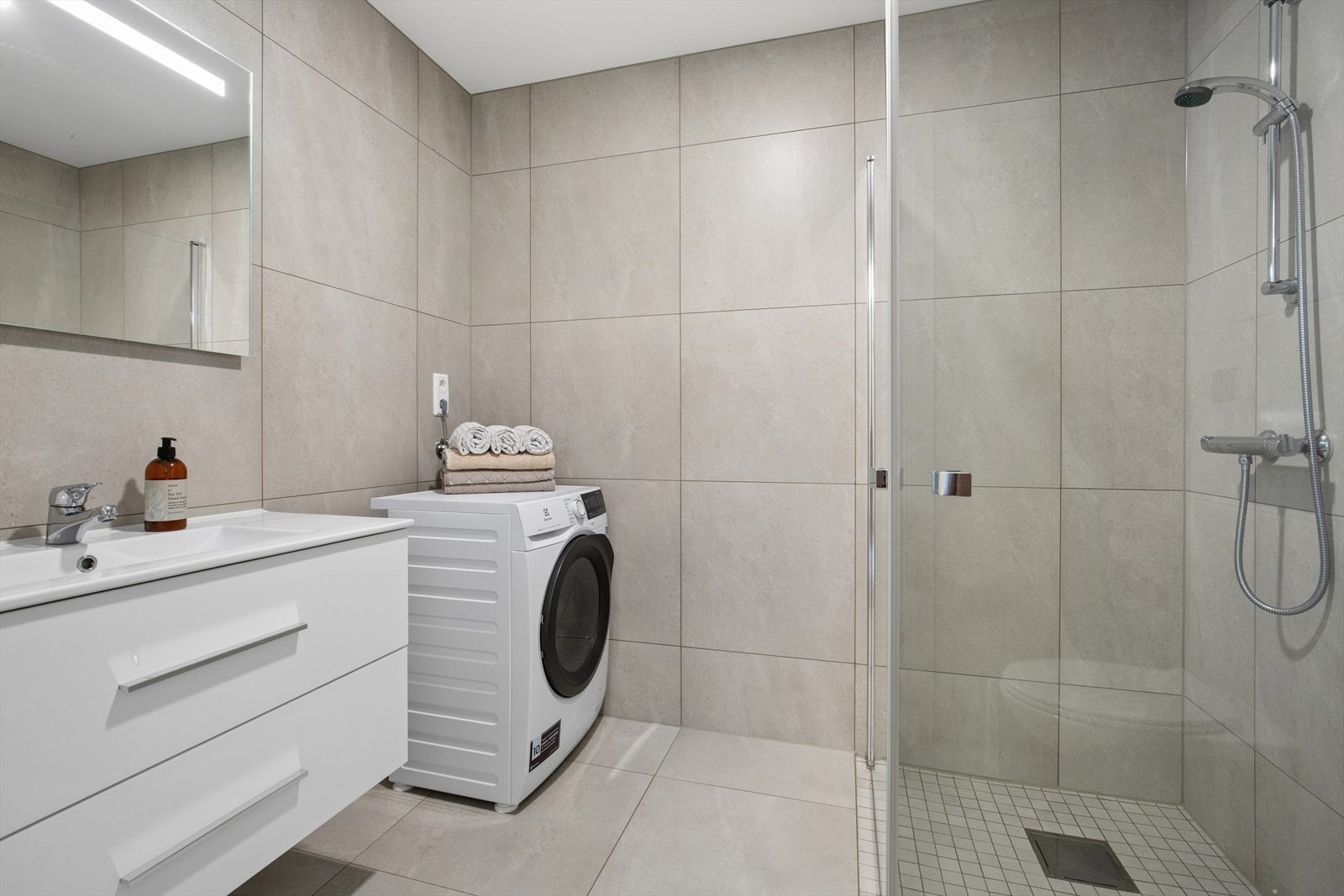 Badet er delikat innredet med store, grå fliser på gulv og vegger. I gulvet har man også varmekabler for ekstra komfort. Galleribilde