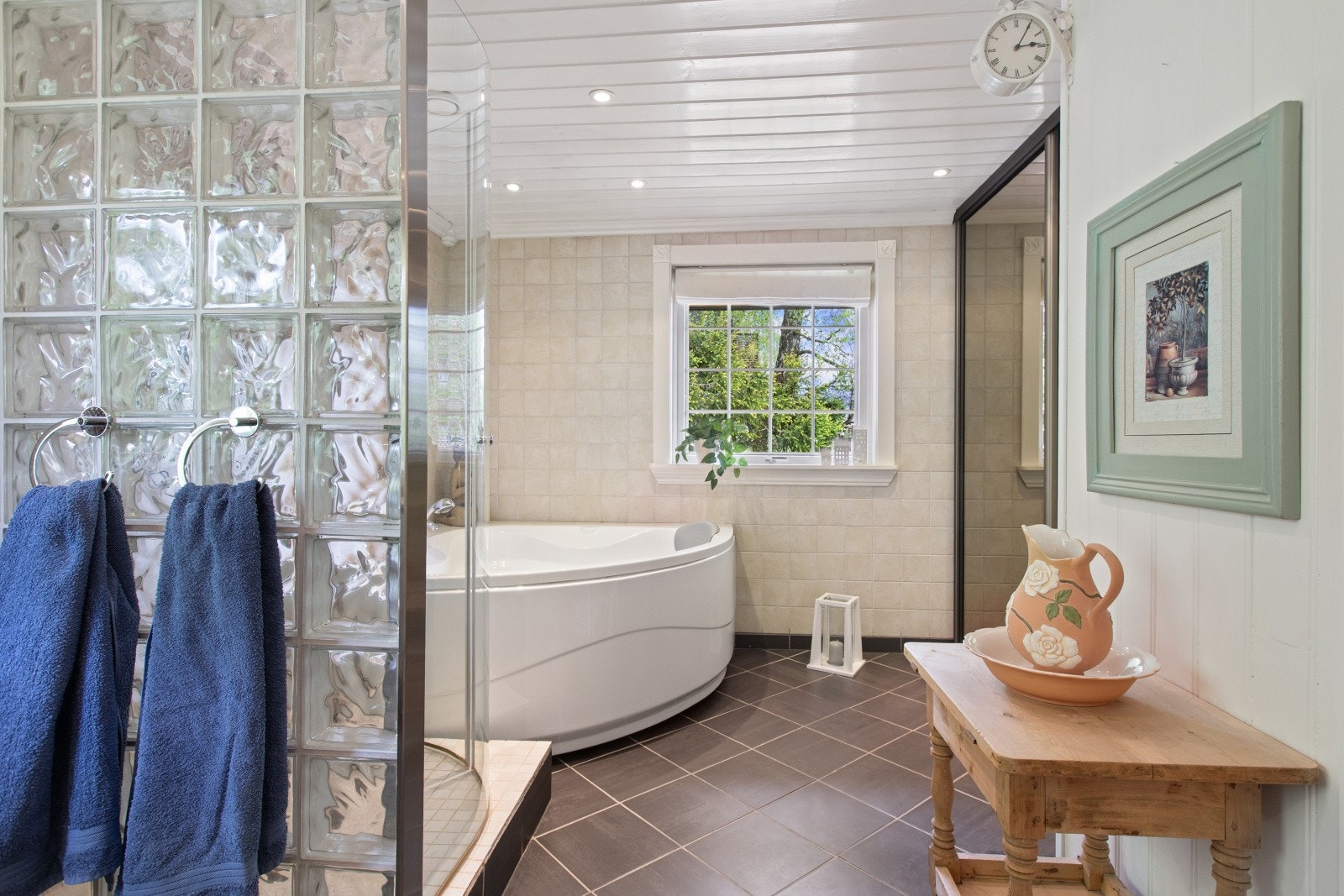 Badet er utstyrt med hjørnebadekar og en dusjnisje med vegger av glassbyggerstein. Galleribilde