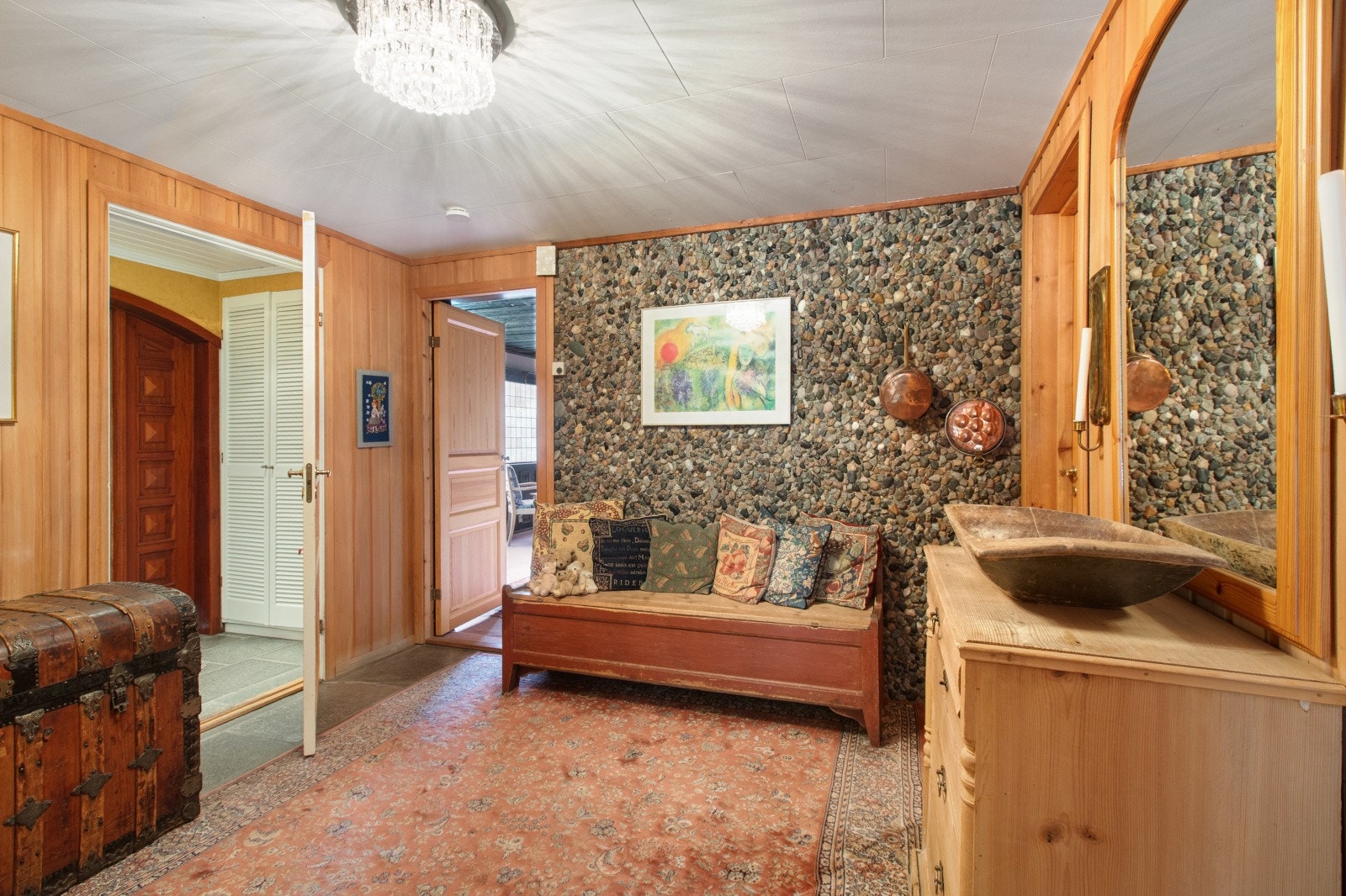 Hallen i underetasjen har en unik panel på veggene, braseliansk furupanel. Det er kontrastvegg i betong med elvestein og god plass til oppbevaring. Galleribilde
