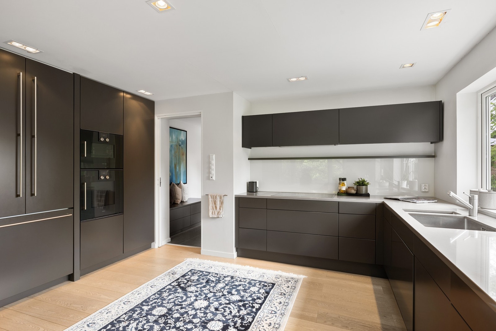 Kjøkken fra 2014 med slette fronter, komposittbenkeplate og fullintegrerte hvitevarer fra Gaggenau. Galleribilde