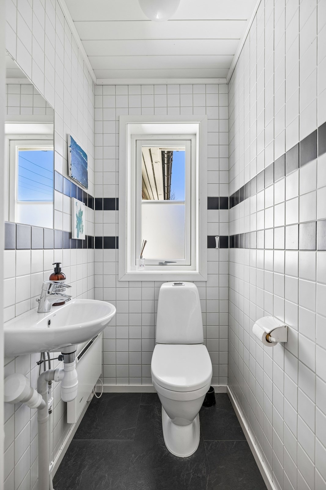 Separat toalettrom i første etasje, med flislagte vegger og gulvmontert WC. Galleribilde