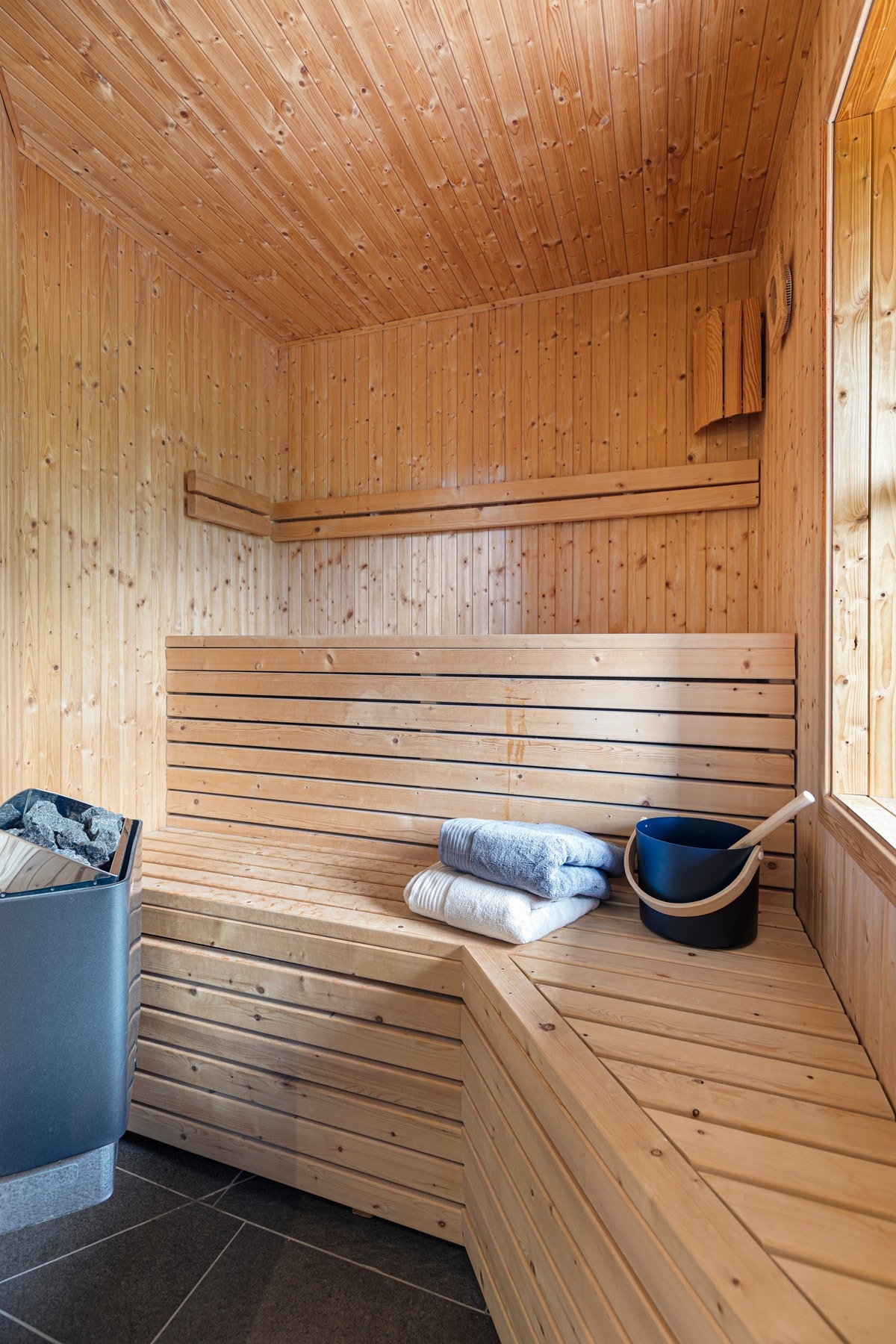Badstuen har fliser på gulv og panel på vegger og himling. Badstuen inneholder sluk i gulv, benker av treverk, badstueovn og inngangsdør av herdet glass. Galleribilde