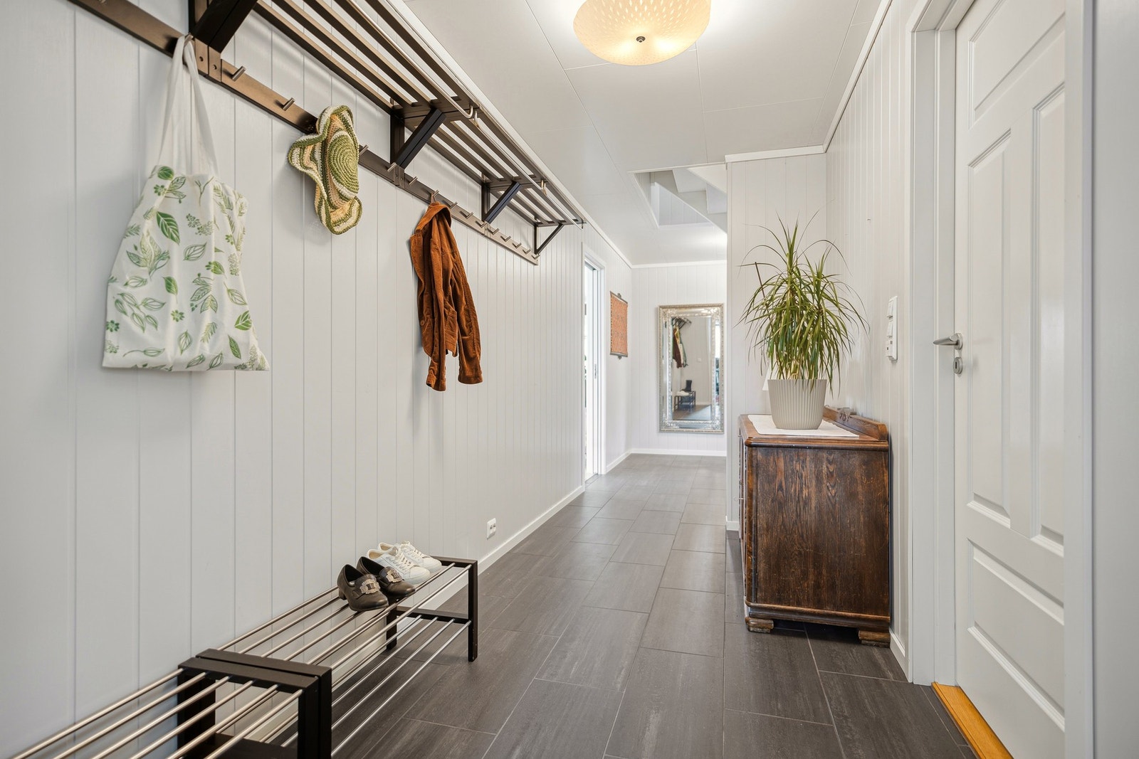 Entréen har god plass til garderobeløsninger og oppbevaring av yttertøy og sko, samtidig som den åpne trappeløsningen bidrar til en luftig og romslig atmosfære. Galleribilde