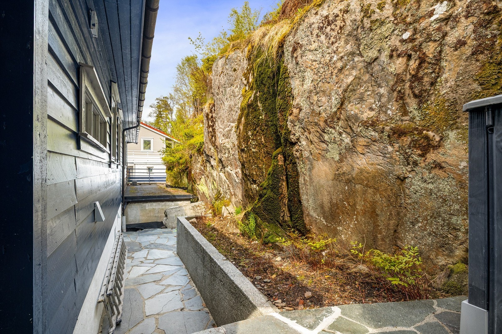 Utgang fra kjøkken til husets bakside. Det er utført bergsikring bak boligen i 2024, og veggen mot baksiden ble etterisolert i 2018. Galleribilde