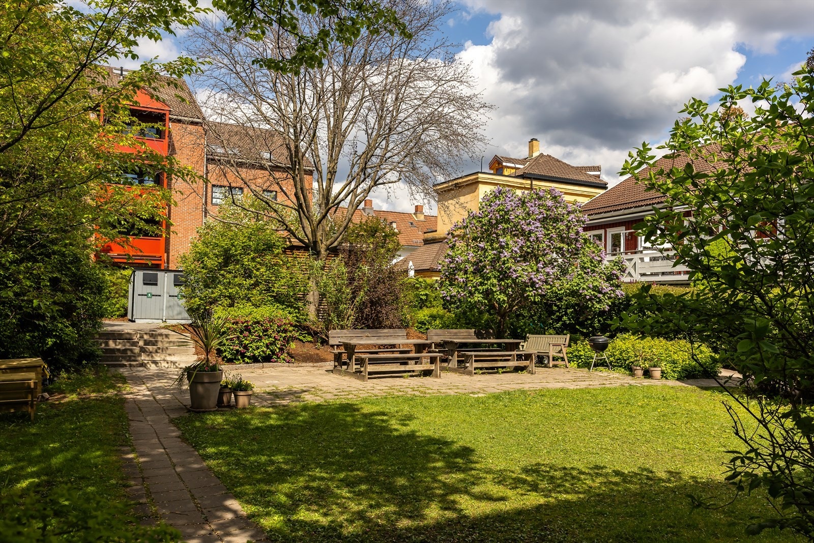 Grønn og frodig felles bakhage med hyggelige sittegrupper, grill og beplantning. Galleribilde