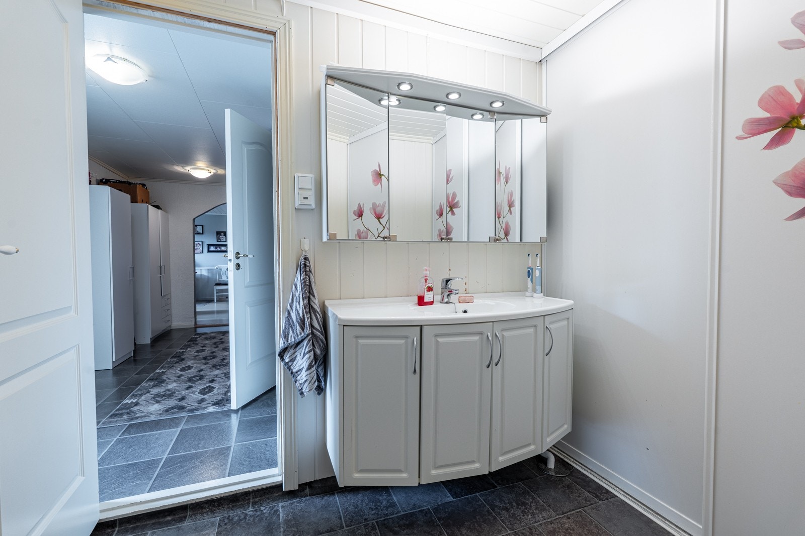 Badet fremstår romslig og delikat, med servant og en innbydende, romslig dusjløsning som gir en følelse av litt ekstra komfort og luksus i hverdagen. Integrert skyvedørsgarderobe gir både god oppbevaringsplass og et stilrent helhetsinntrykk. Galleribilde