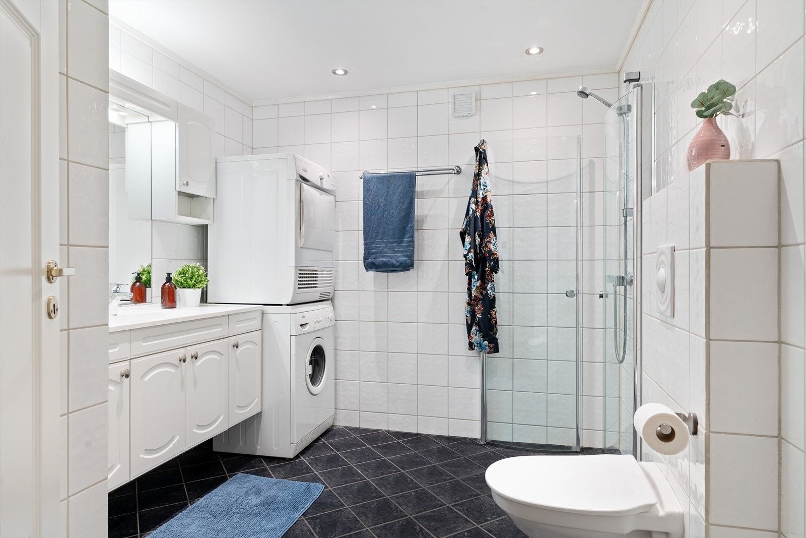 Det 5,9 kvm store badet er flislagt med behagelig gulvvarme. Det er god plass til oppbevaring av baderomsartikler i skuffer og skap. Galleribilde