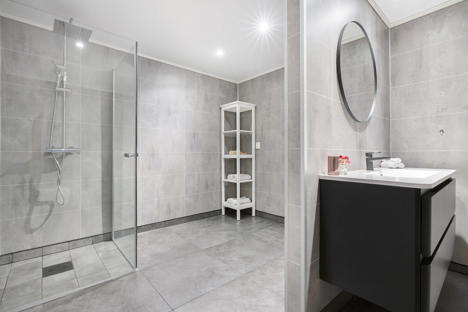 Badet har dusjhjørne med glassvegger, veggmontert toalett og opplegg for vaskemaskin. Galleribilde