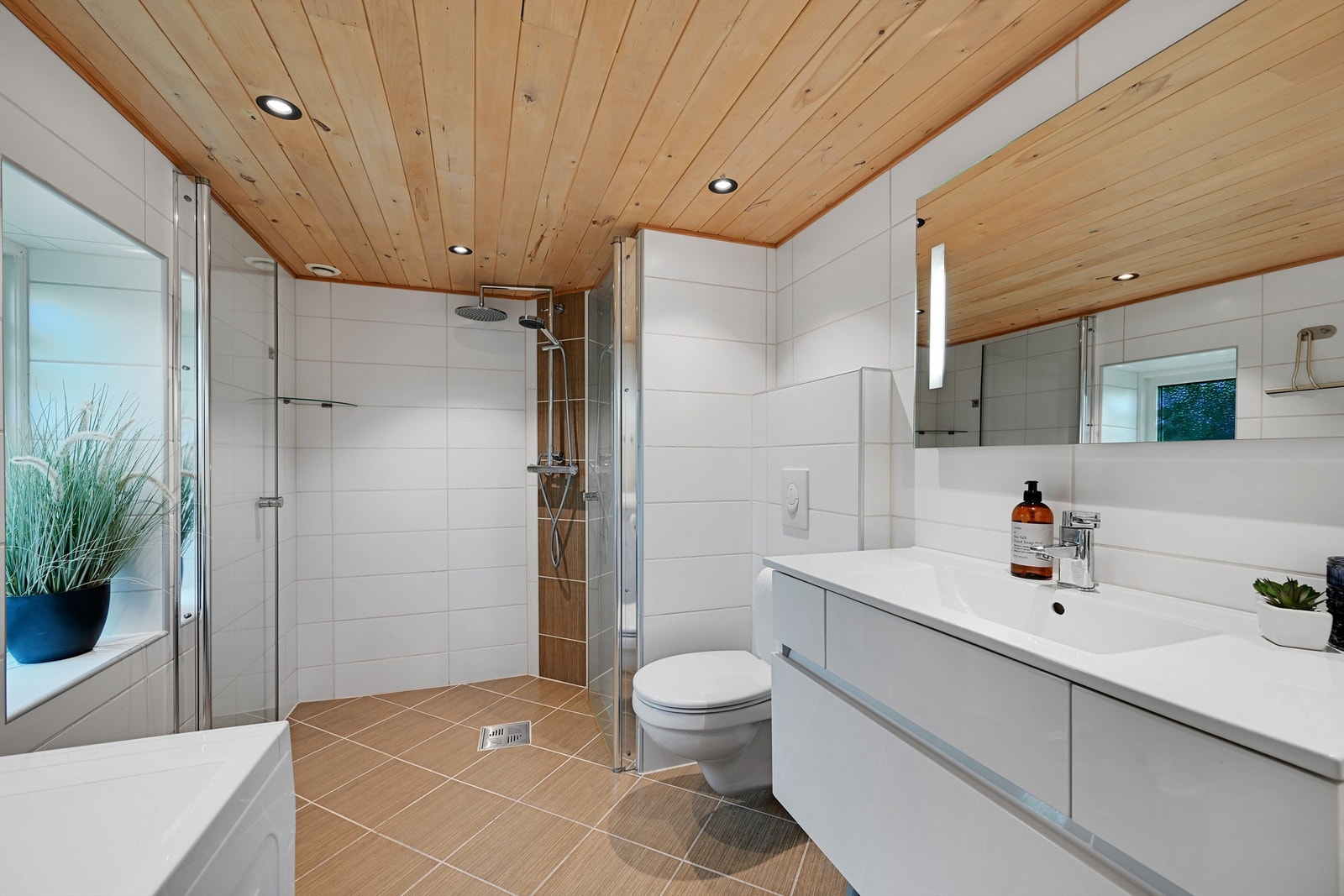 Badet fra 2012 er moderne og delikat innredet med heldekkende servant, vegghengt toalett, dusj med glassvegger og opplegg for vaskemaskin. Galleribilde
