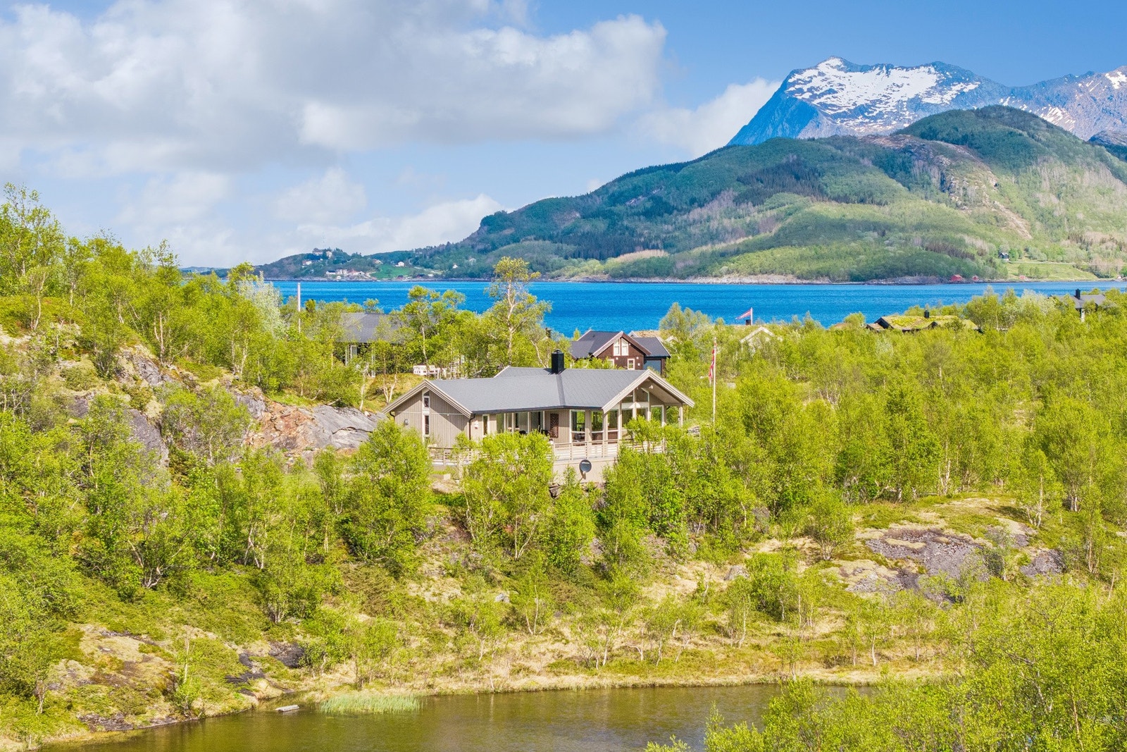 Hytta ligger vakkert til i terrenget, omkranset av bjørkeskog og med nærhet til sjøen. Galleribilde