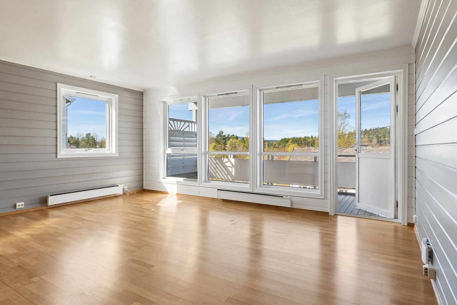 Stuen har store vinduer og balkongdør som flommer over med naturlig lys noe som gir en åpen og luftig følelse Galleribilde