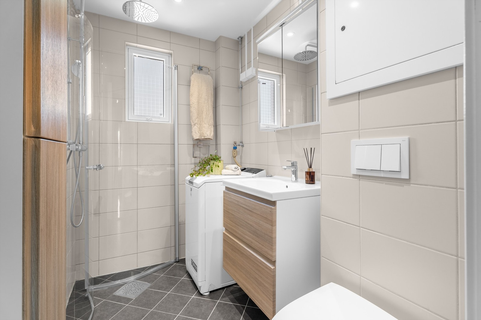 Badet er utstyrt med dusjhjørne med svingbar glassdør, veggmontert toalett, samt opplegg for vaskemaskin av smal type. Galleribilde