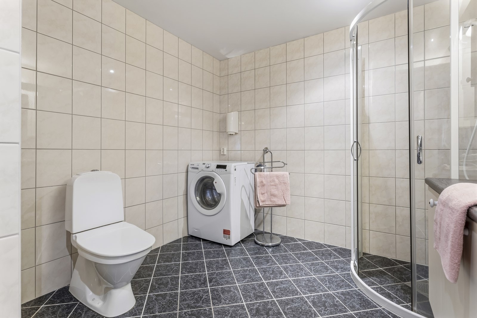 Badet er utstyrt med dusj, toalett, opplegg for vaskemaskin og baderomsinnredning med servant samt belyst speil. Galleribilde