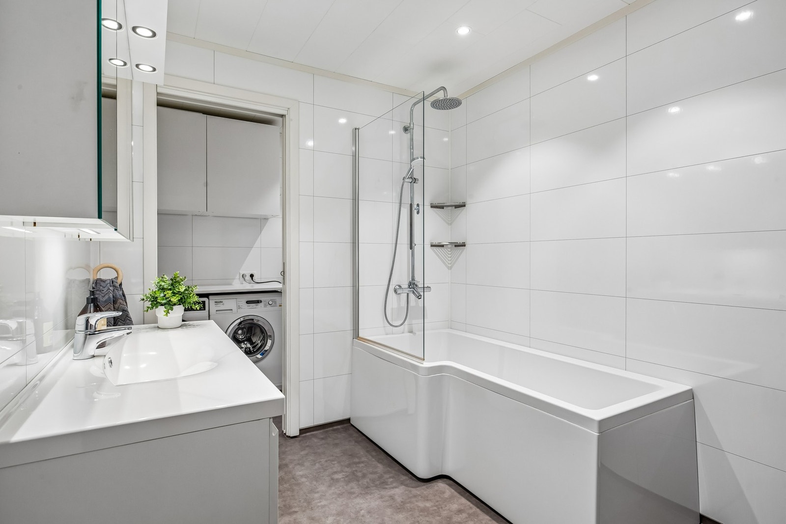 Delikat bad med bl.a. downlights i himling, badekar med dusj og baderomsinnredning med heldekkende servant. Galleribilde